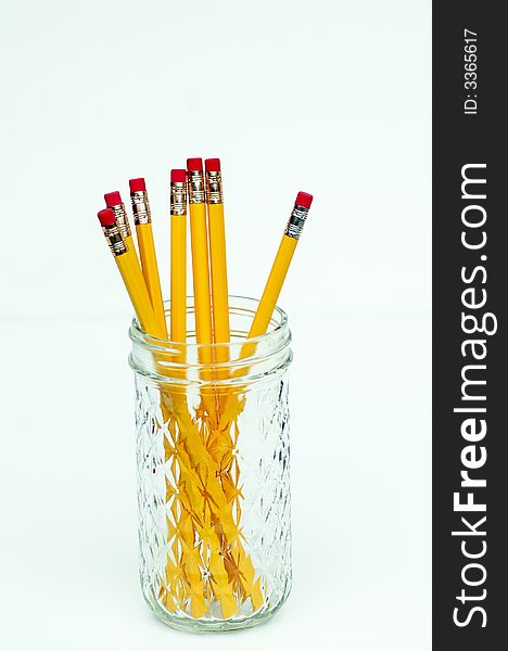 Eight yellow pencils in patterned glass jelly jar, isolated against white. Eight yellow pencils in patterned glass jelly jar, isolated against white