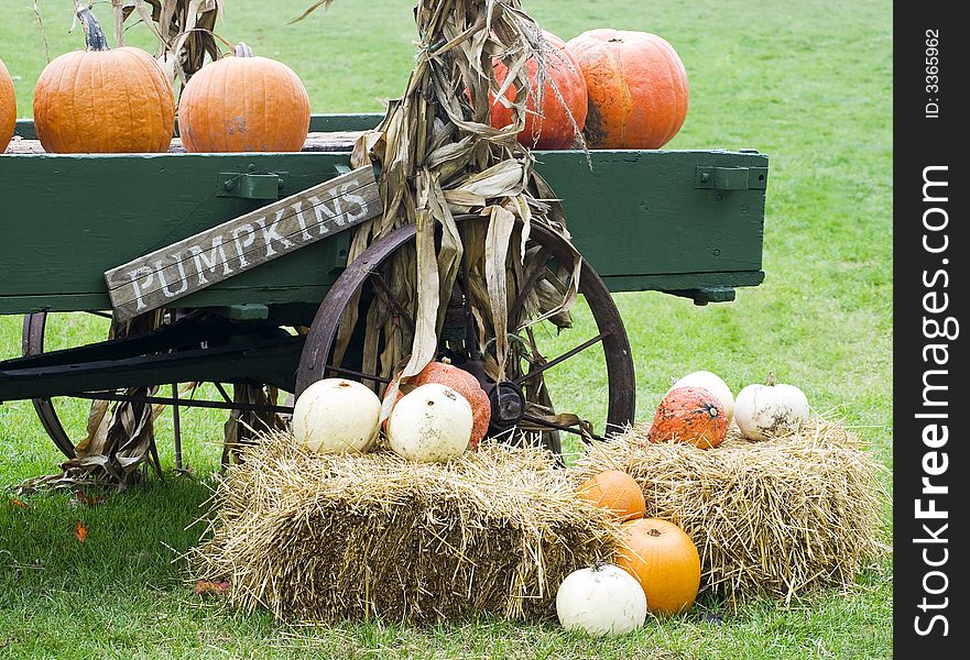 Autumn seasonal display of pumpkins, gourds and straw bales by an old wagon. Autumn seasonal display of pumpkins, gourds and straw bales by an old wagon