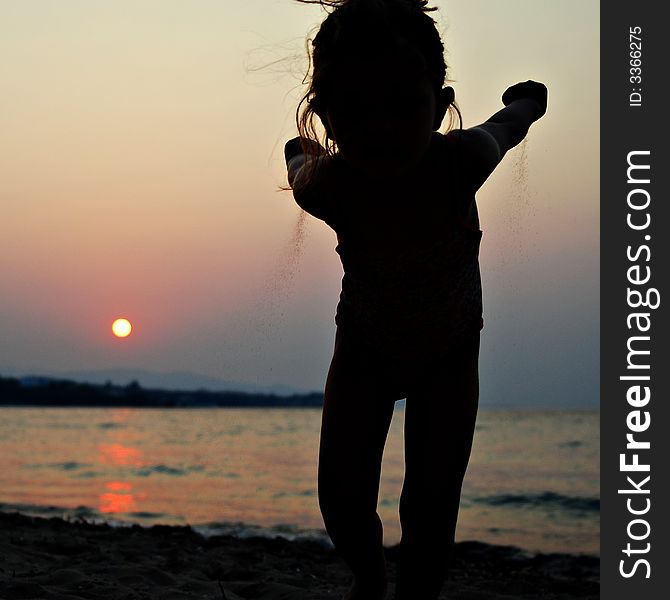 Young kid girl throwing sand on sunset beach. Young kid girl throwing sand on sunset beach