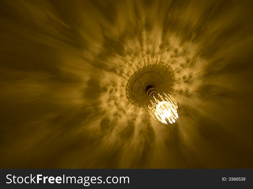 Light plays across the ceiling as a chandelier lights it. Light plays across the ceiling as a chandelier lights it
