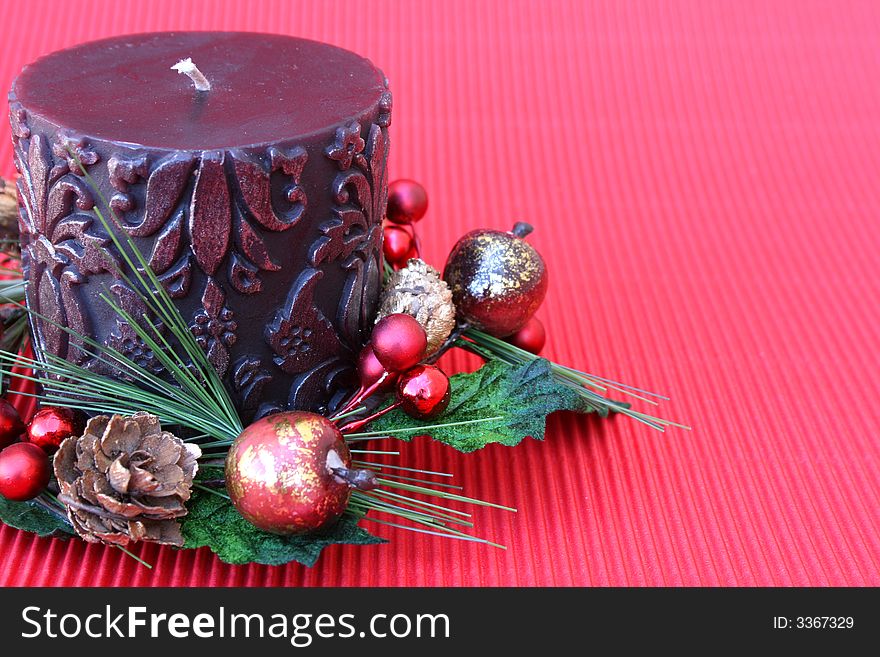 Dark pattern candle with a small christmas wreath around it. Dark pattern candle with a small christmas wreath around it