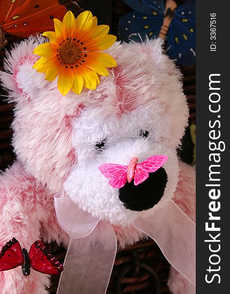 A pink teddy bear with a butterfly on its nose