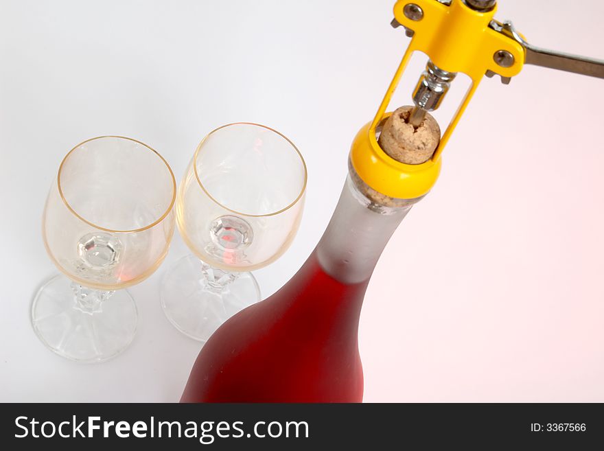 A bottle of red wine and yellow corkscrew. A bottle of red wine and yellow corkscrew