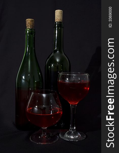 Red wine bottles and glasses isolated over black. Red wine bottles and glasses isolated over black