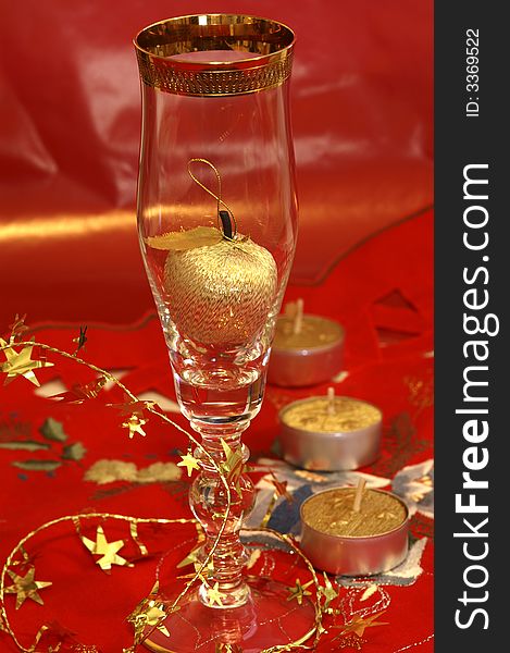 Red CHristmas table-cloth with golden apple in CHampagne glass. Red CHristmas table-cloth with golden apple in CHampagne glass