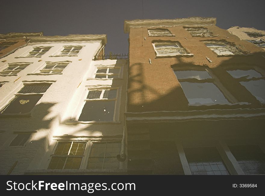 Streets of Delft, a small town in Holland, the area of the city centre and neighbouring streets with row houses made of red bricks, built over a century ago. This picture is a reflection of the building in the canal.