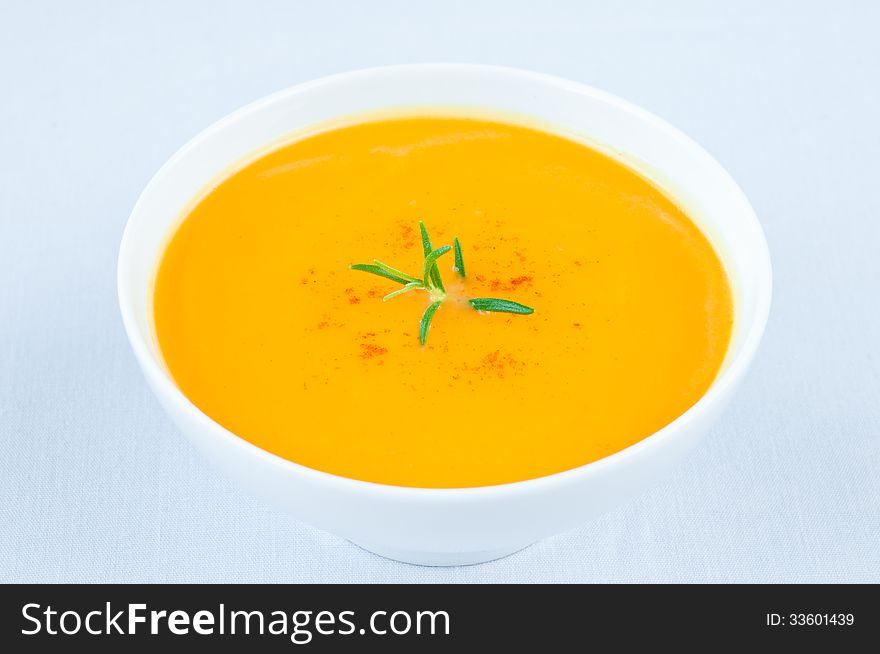 Fresh pumpkin soup in white bowl with rosemary on top. Fresh pumpkin soup in white bowl with rosemary on top