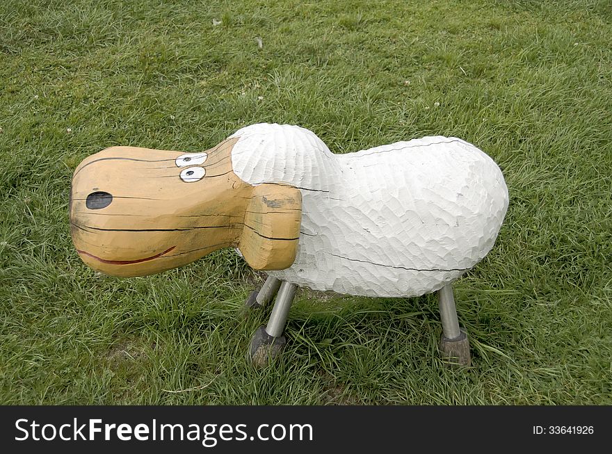 Sheep of wood, on a grass in a park playground.