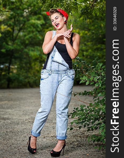 Beautiful pin-up girl in denim overalls and a T-shirt outdoors