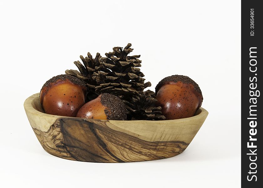 Pine cones and pine nuts in a patterned wood bowl against a white background. Pine cones and pine nuts in a patterned wood bowl against a white background