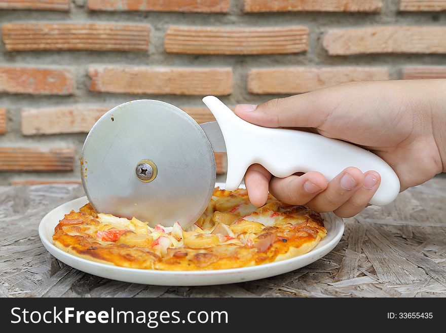 Hand cutting tasty pizza cheese