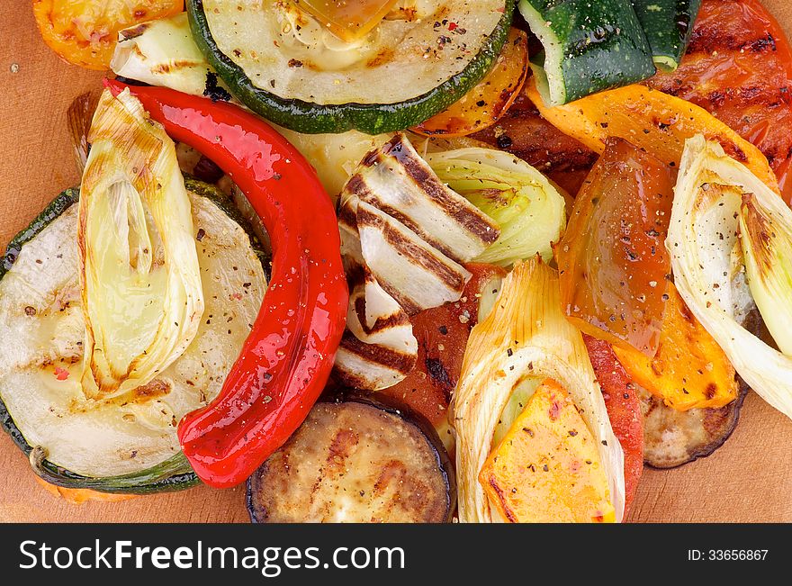 Various Grilled Vegetables with Chili Pepper and Spices closeup on Wooden Cutting Board. Top View