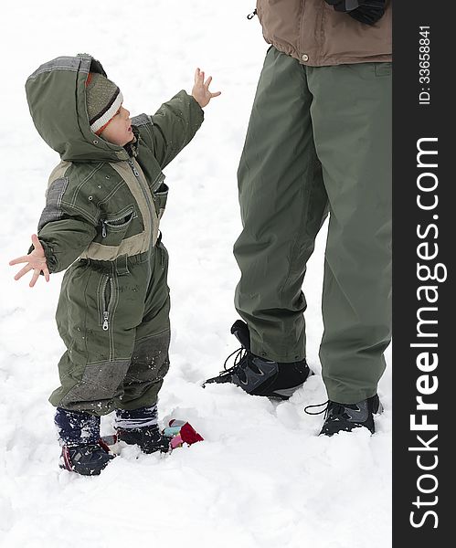 Child toddler in winter snow showing his cold hands to a father or parent. Child toddler in winter snow showing his cold hands to a father or parent.