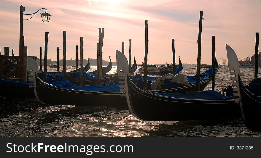 Gondola's slightly silhouetted against the bright morning sky, on the water front of the San Marco Canal and Palazzo Ducal. Gondola's slightly silhouetted against the bright morning sky, on the water front of the San Marco Canal and Palazzo Ducal.