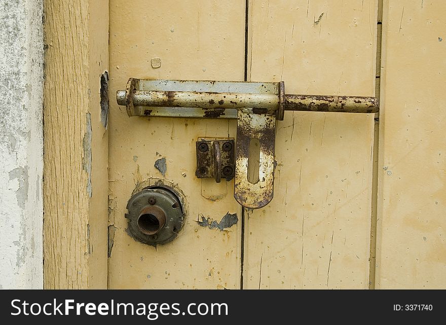 A Rusty Padlock on a yellow wooden door