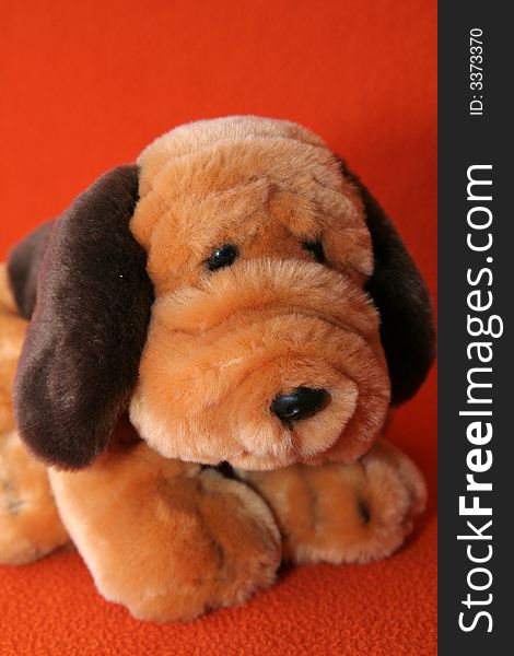 Plush dog against dark orange background. Plush dog against dark orange background