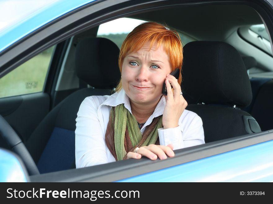 Red-haired woman with mobile-phone in a car. She is thinking oups. Red-haired woman with mobile-phone in a car. She is thinking oups