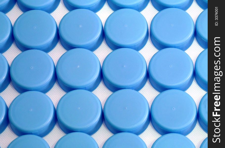 An assortment of blue water bottle caps laid in a grid formation