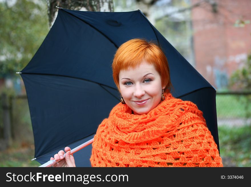 Young red-haired woman in red scarf with umbrella. Young red-haired woman in red scarf with umbrella