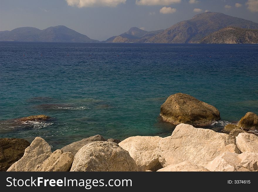 Mediterranean landscape with big stones in front and silhouette of mountains background. Mediterranean landscape with big stones in front and silhouette of mountains background