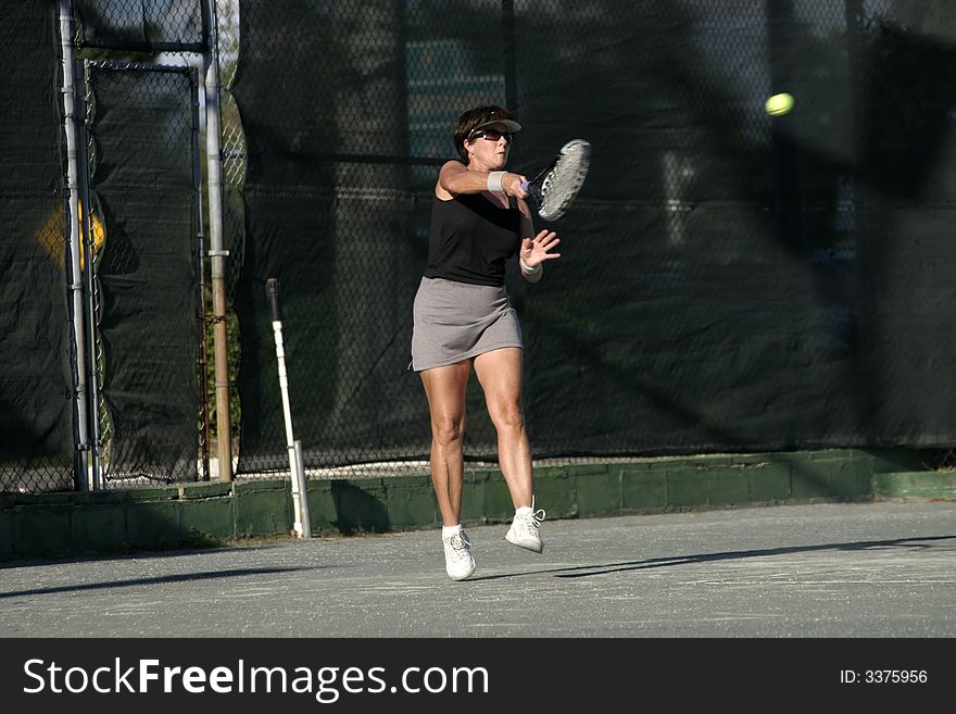 Middle aged female tennis player in action. Middle aged female tennis player in action