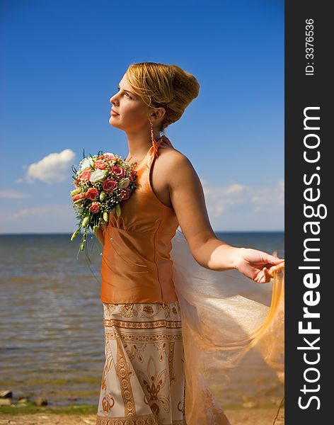 Lovely redhead lady with a bouquet of flowers near the sea