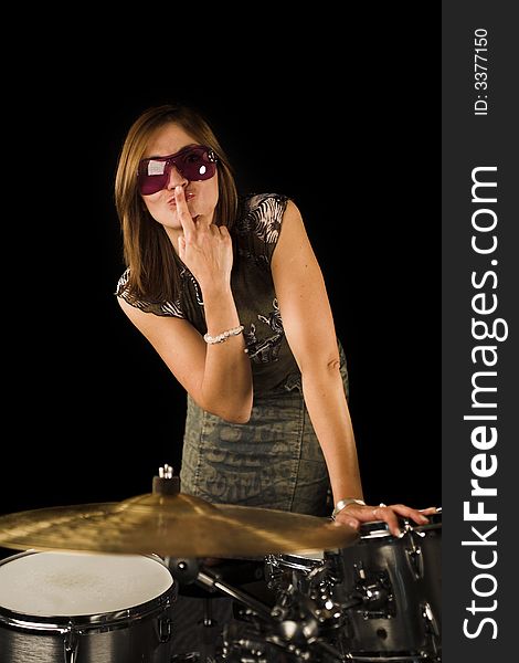 Woman with expression on drum set over black backdrop