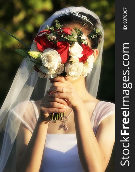 Bride holding her bouquet in front of her face in her wedding day. Bride holding her bouquet in front of her face in her wedding day