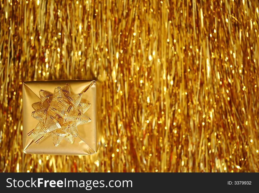 A Christmas box - a golden cube with golden ribbon, golden strings in the background. A Christmas box - a golden cube with golden ribbon, golden strings in the background.