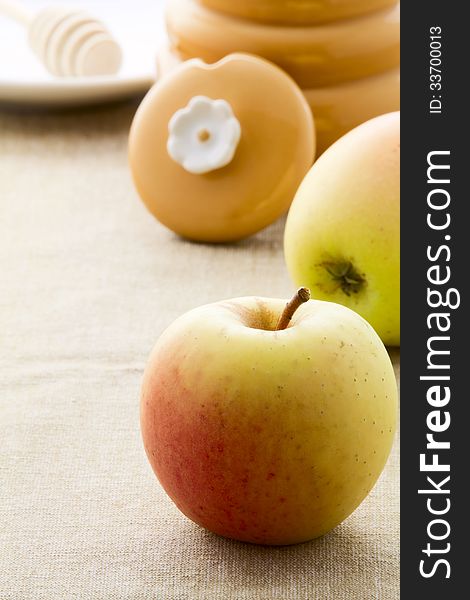 On the table ripe apples and crockery for honey