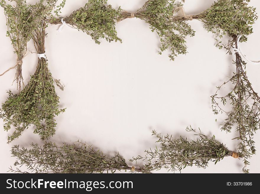 Bundles of drying thyme and savory herb create a frame against a white background with copy space. Bundles of drying thyme and savory herb create a frame against a white background with copy space.