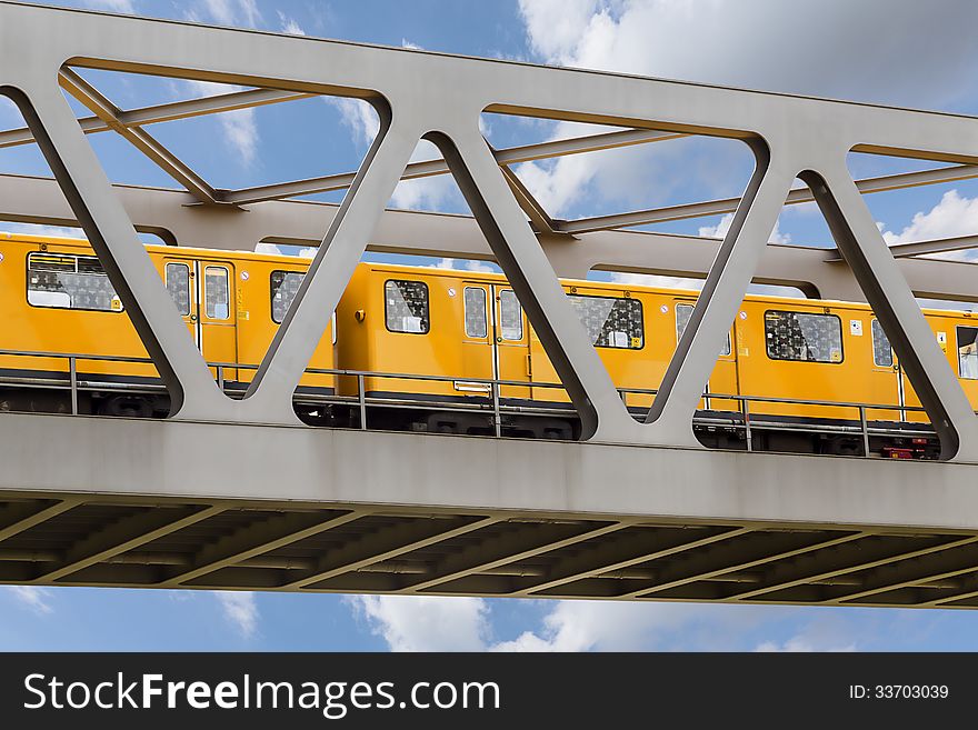 Yellow moving train on an iron bridge with blue sky