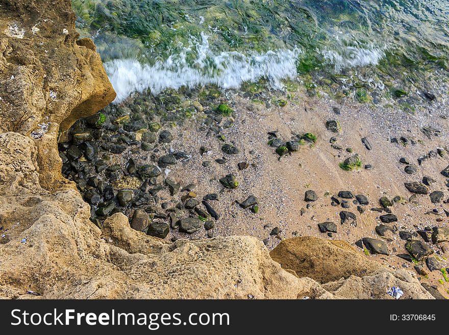 Wave rolls onto the rocks on the sandy sea coast. Wave rolls onto the rocks on the sandy sea coast