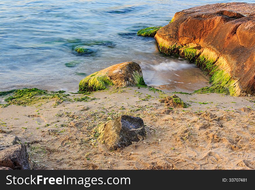 Sea wave strugle with stone on the sandy beach