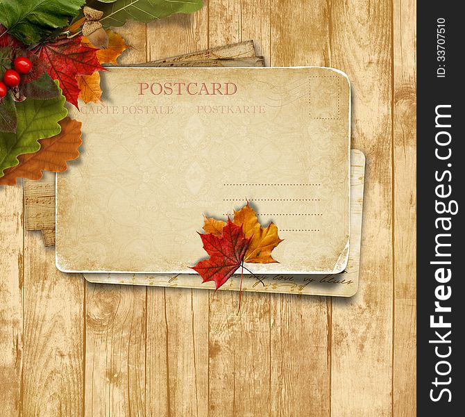 Autumn leaves over wooden background with postcard
