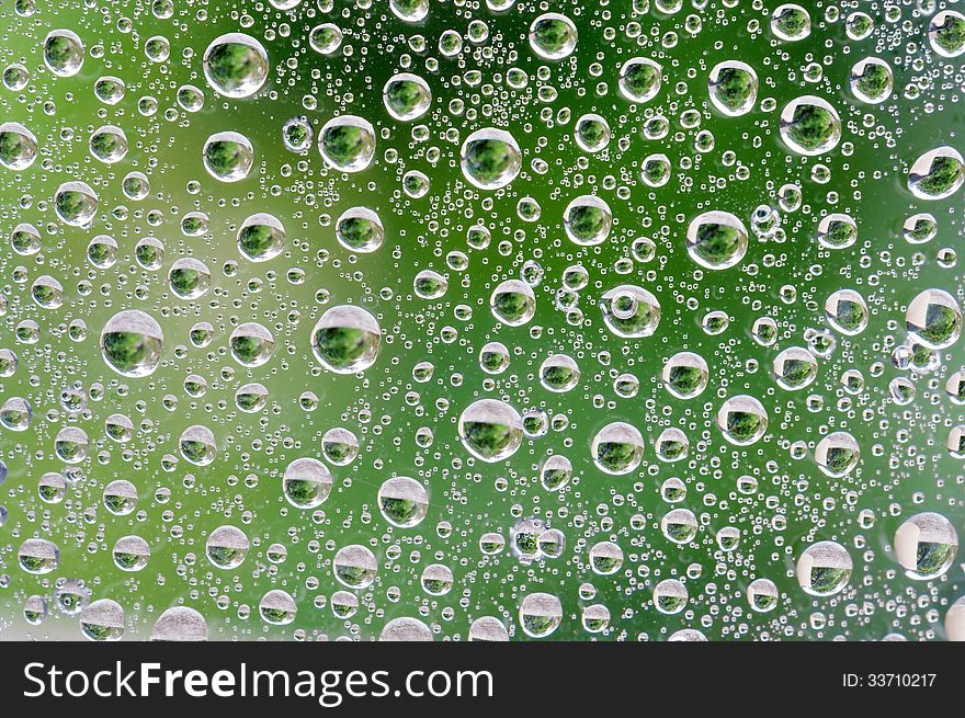 Water Drops on window with green background.