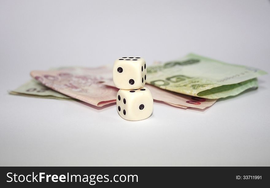 2 dices stack on each other with thai banknotes on white background. 2 dices stack on each other with thai banknotes on white background.