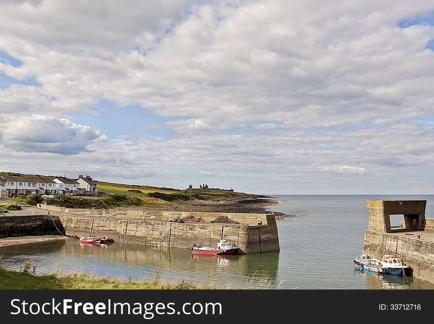 A view of Craster Harbour with Dunstanburgh Castle in the distance