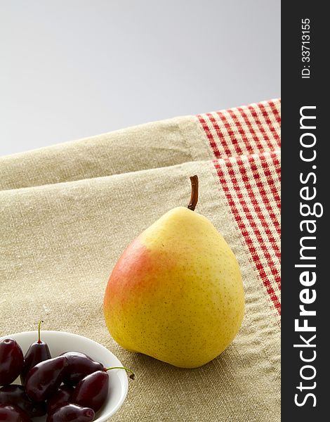 Ripe pear and dogwood berries on a linen napkin