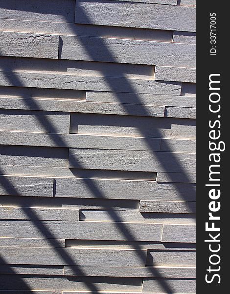 Textured wall made of white bricks and diagonal shadows.