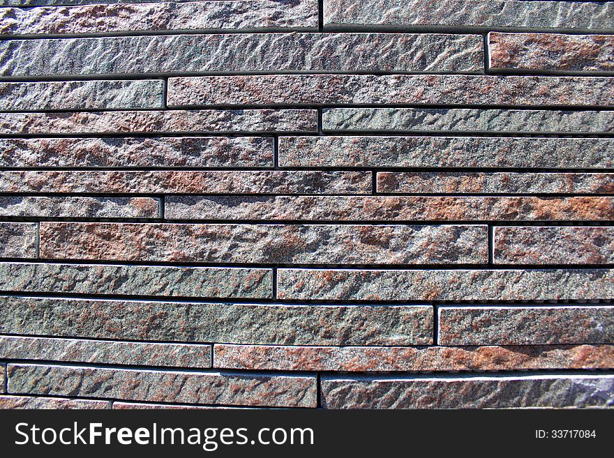 Stone wall cladding, pattern by modern wall of bricks sunlight.