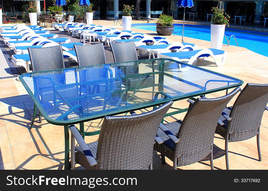 Rattan furniture at patio near pool and sunbeds