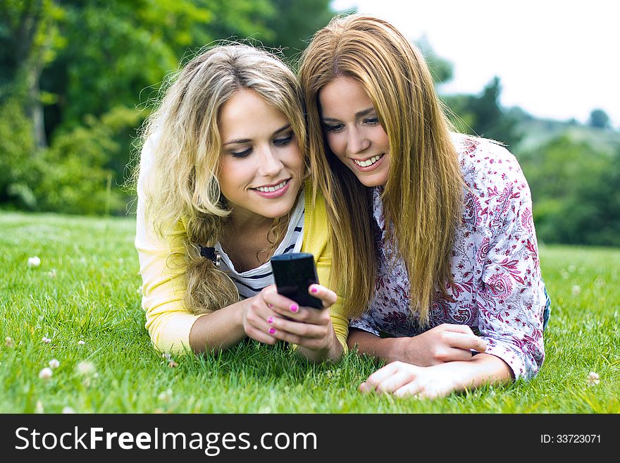 Portrait of two sisters with smartphone at the park