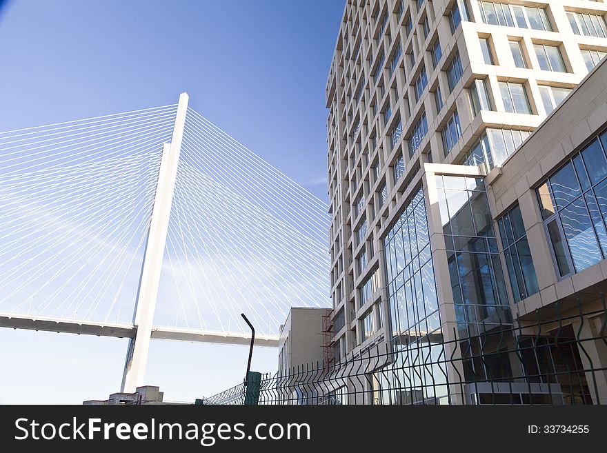 Big suspension bridge in beams of the coming sun against the blue sky