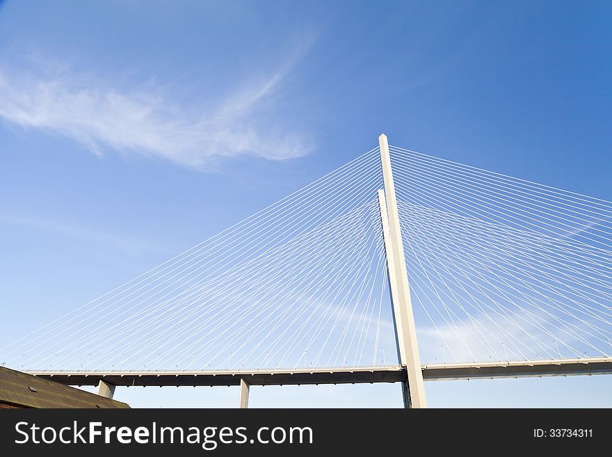 Big suspension bridge in beams of the coming sun against the blue sky