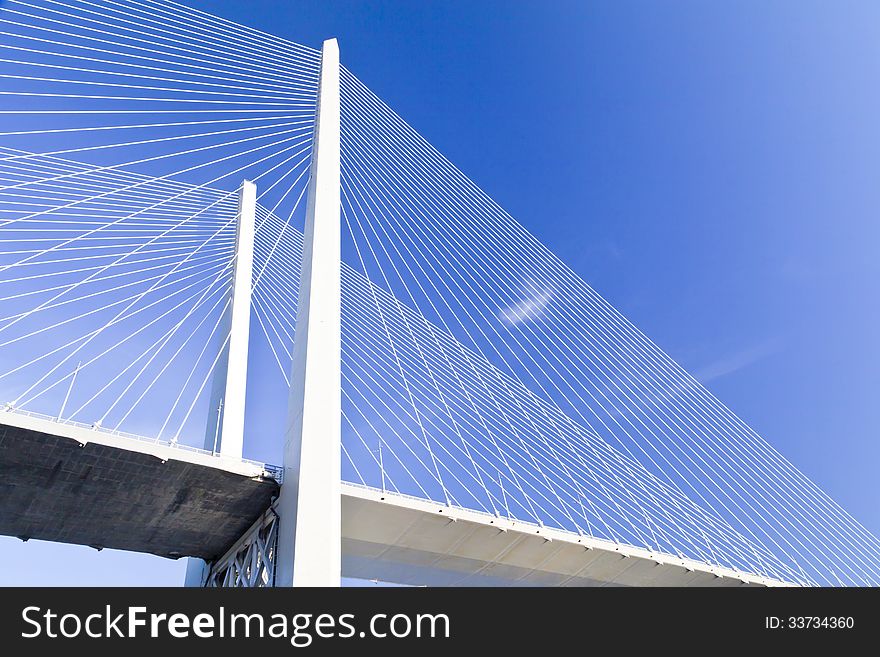 Big suspension bridge in beams of the coming sun against the blue sky