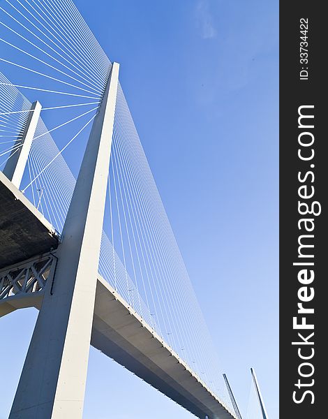 Big suspension bridge in beams of the coming sun against the blue sky