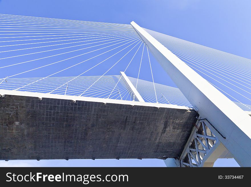 Big suspension bridge in beams of the coming sun against the blue sky