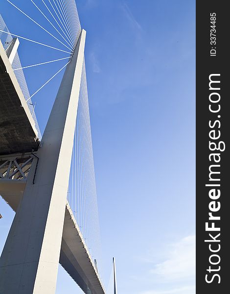 Big suspension bridge in beams of the coming sun against the blue sky