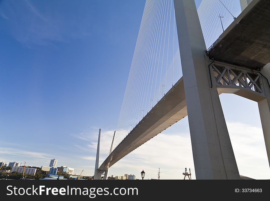 Big suspension bridge in beams of the coming sun against the blue sky